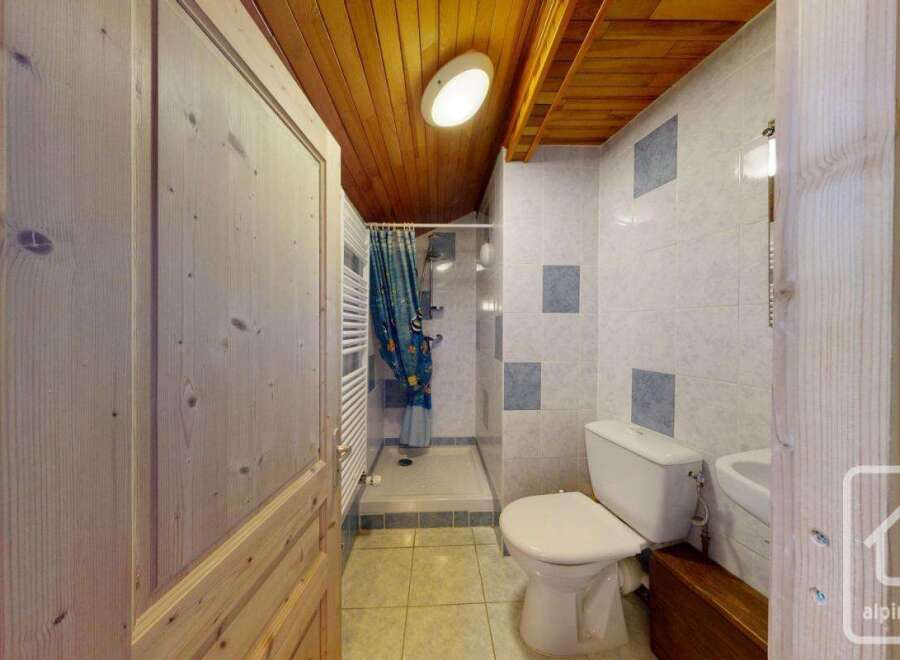 Step into this charming bathroom, featuring a cozy wooden ceiling and walls that exude warmth.