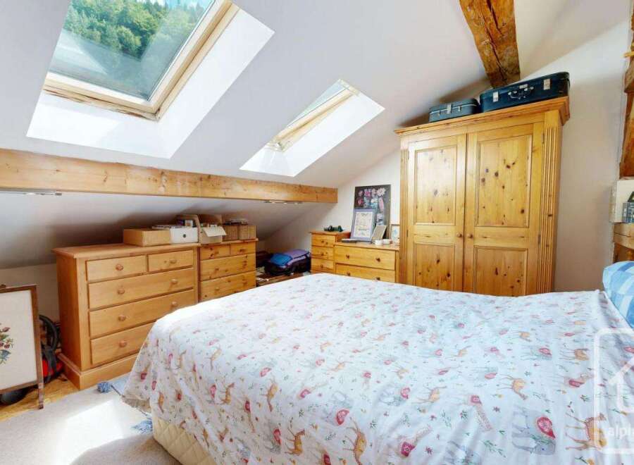 This charming bedroom features a cozy bed with a unique patterned duvet, complemented by wooden furniture that adds warmth and character.