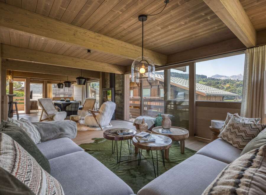 Experience luxury living in this stunning chalet, featuring a cozy living room with a plush sofa and a unique coffee table.