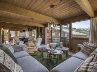Experience luxury living in this stunning chalet, featuring a cozy living room with a plush sofa and a unique coffee table.