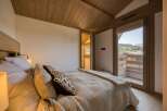 This cozy bedroom features a wooden ceiling and a large window offering stunning views of the surrounding landscape.