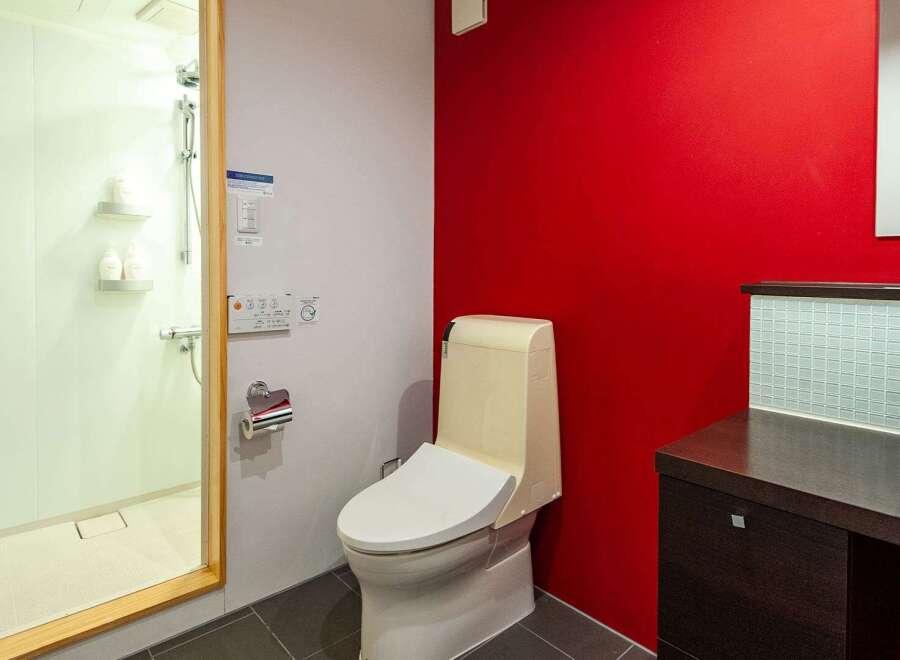 This modern bathroom features a sleek design with a vibrant red accent wall, creating a bold and stylish atmosphere.