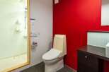This modern bathroom features a sleek design with a vibrant red accent wall, creating a bold and stylish atmosphere.