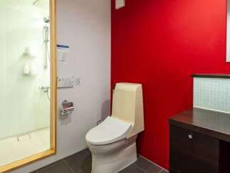 This modern bathroom features a sleek design with a vibrant red accent wall, creating a bold and stylish atmosphere.