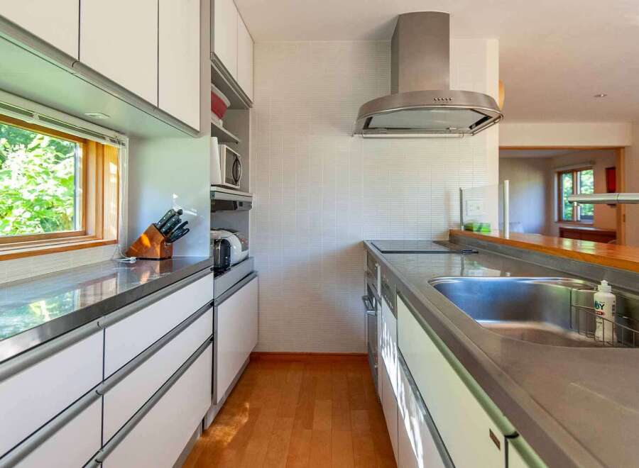 This modern kitchen boasts sleek stainless steel countertops and white cabinetry, creating a bright and airy space.