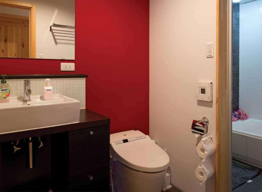 This modern bathroom features a sleek design with a red accent wall, creating a vibrant and inviting atmosphere.