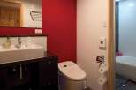 This modern bathroom features a sleek design with a red accent wall, creating a vibrant and inviting atmosphere.