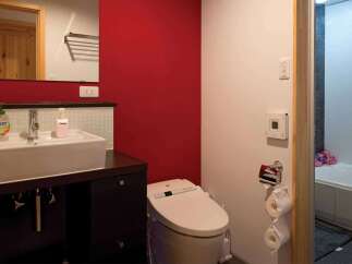 This modern bathroom features a sleek design with a red accent wall, creating a vibrant and inviting atmosphere.