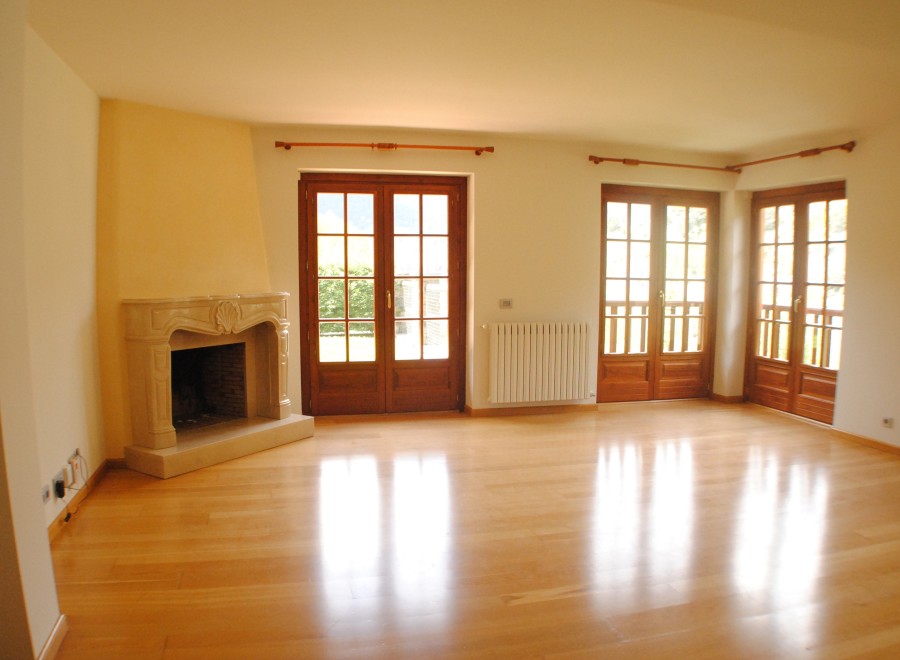 This stunning property boasts a spacious living area with gleaming hardwood floors and large wooden doors that flood the room with natural light.