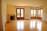 This stunning property boasts a spacious living area with gleaming hardwood floors and large wooden doors that flood the room with natural light.