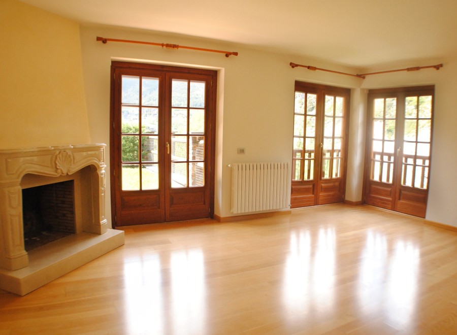 Bright and airy living room with hardwood floors and large wooden doors leading to a scenic view.