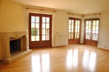 Bright and airy living room with hardwood floors and large wooden doors leading to a scenic view.