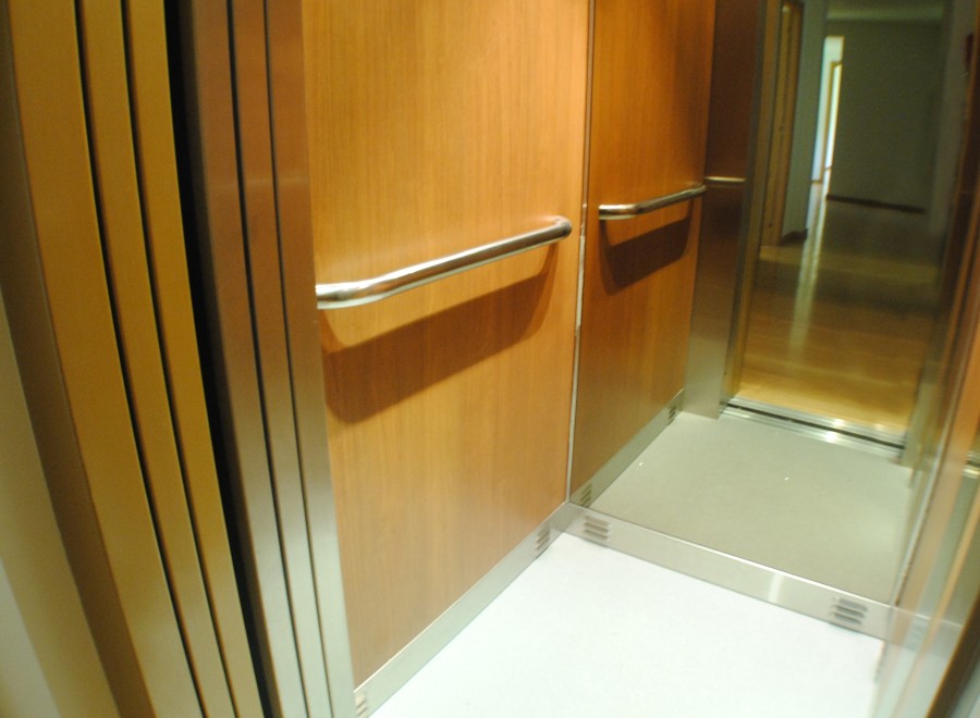 Modern elevator with wood paneling and stainless steel accents.