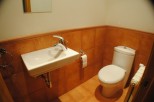 This cozy bathroom boasts a modern toilet and sink, complemented by warm, terracotta-colored tile flooring and walls.