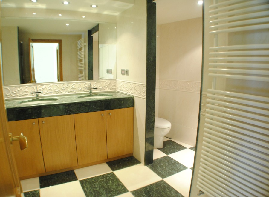 This stunning bathroom boasts a spacious double vanity with marble countertops and wooden cabinets, offering ample storage.