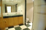 This stunning bathroom boasts a spacious double vanity with marble countertops and wooden cabinets, offering ample storage.
