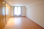 Spacious room with terracotta tile flooring and built-in wooden wardrobes.