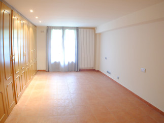 Spacious room with terracotta tile flooring and built-in wooden wardrobes.