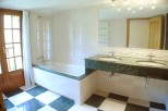 This luxurious bathroom boasts a spacious bathtub with a glass enclosure, complemented by a stylish green marble double vanity with modern fixtures.