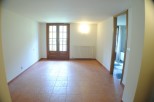 This spacious room boasts terracotta tile flooring and large wooden doors that lead to outdoor access.