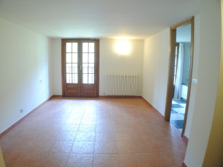 This spacious room boasts terracotta tile flooring and large wooden doors that lead to outdoor access.