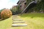 This stunning property boasts a charming stone exterior, lush landscaping, and a unique wooden staircase leading to a modern metal staircase.