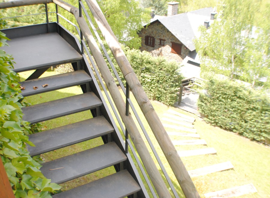 This stunning property boasts a unique outdoor staircase with metal steps and wooden railings, offering breathtaking views of the surrounding landscape.