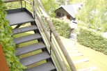 This stunning property boasts a unique outdoor staircase with metal steps and wooden railings, offering breathtaking views of the surrounding landscape.