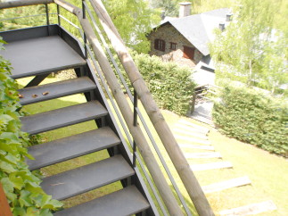 This stunning property boasts a unique outdoor staircase with metal steps and wooden railings, offering breathtaking views of the surrounding landscape.