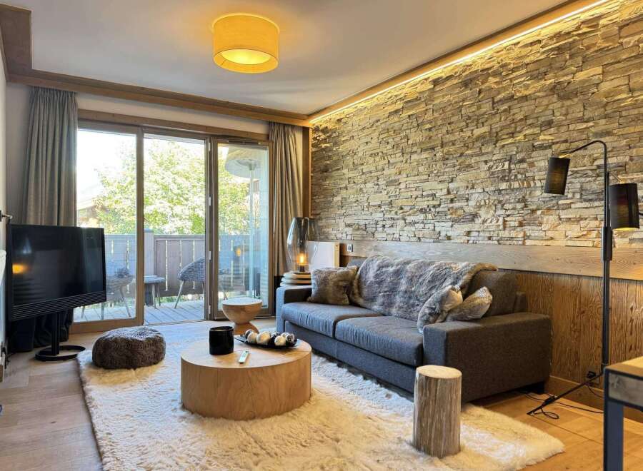 Experience luxury living in this stunning property, featuring a cozy living room with a stone wall and a plush rug.