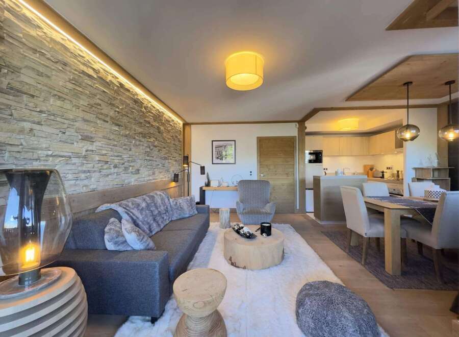 Experience luxury living in this stunning property, featuring a cozy living room with a stone wall and a modern sofa.