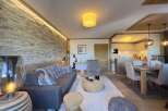 Experience luxury living in this stunning property, featuring a cozy living room with a stone wall and a modern sofa.