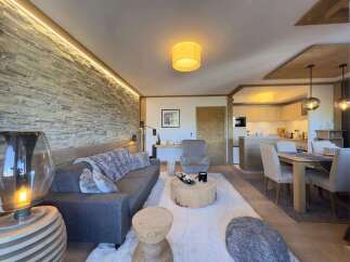 Experience luxury living in this stunning property, featuring a cozy living room with a stone wall and a modern sofa.