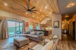 This stunning property boasts a spacious living area with a vaulted, wood-paneled ceiling and a modern ceiling fan.