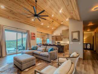This stunning property boasts a spacious living area with a vaulted, wood-paneled ceiling and a modern ceiling fan.