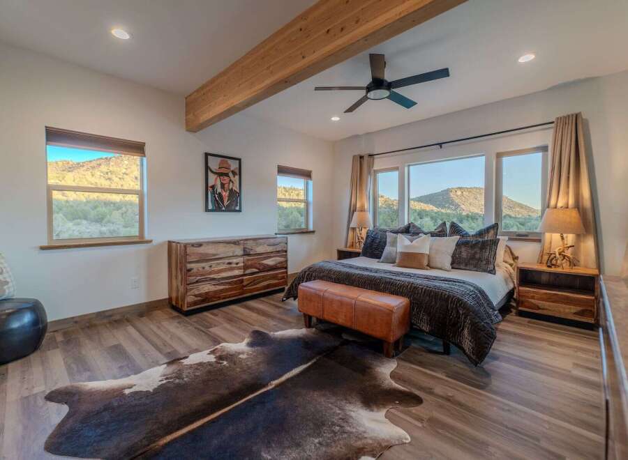 Experience luxury in this stunning bedroom featuring a rustic wooden dresser and a cozy leather bench.