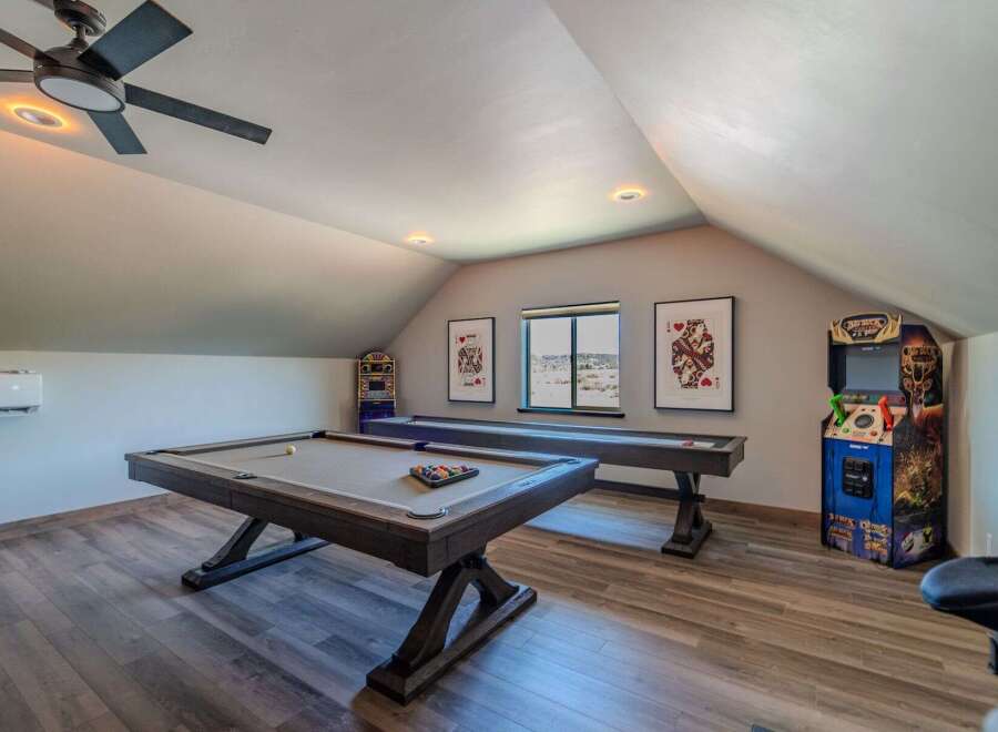 This stunning game room features a pool table, shuffleboard, and arcade game, perfect for entertaining guests.