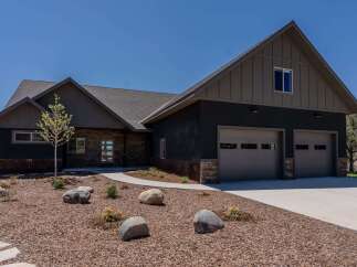 This stunning property boasts a modern design with a sleek, dark exterior and a welcoming facade.