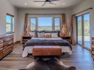 Experience luxury in this stunning bedroom featuring a king-size bed, a cozy leather bench, and a cowhide rug.