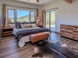 Experience luxury living in this stunning bedroom featuring a plush bed, a stylish leather bench, and a unique cowhide rug.