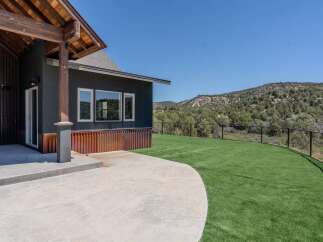 This stunning property boasts a modern design with a sleek, dark exterior and a spacious concrete patio, perfect for outdoor entertaining.