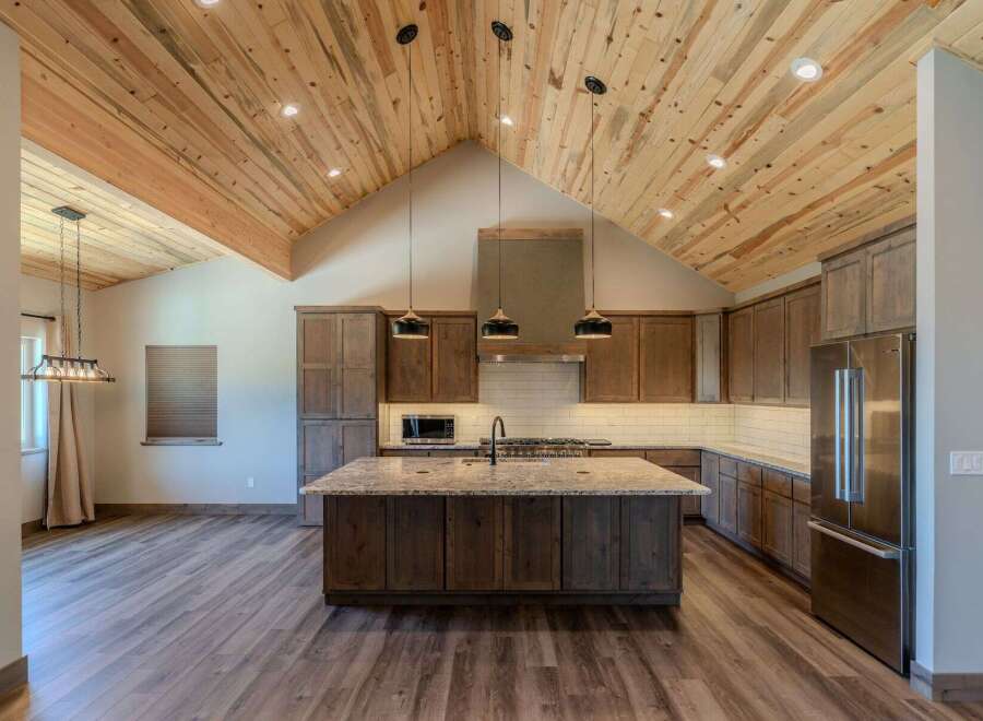 Experience luxury living in this stunning kitchen featuring a vaulted wood-plank ceiling and a large granite island perfect for entertaining.