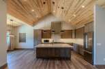 Experience luxury living in this stunning kitchen featuring a vaulted wood-plank ceiling and a large granite island perfect for entertaining.