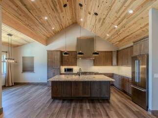 Experience luxury living in this stunning kitchen featuring a vaulted wood-plank ceiling and a large granite island perfect for entertaining.