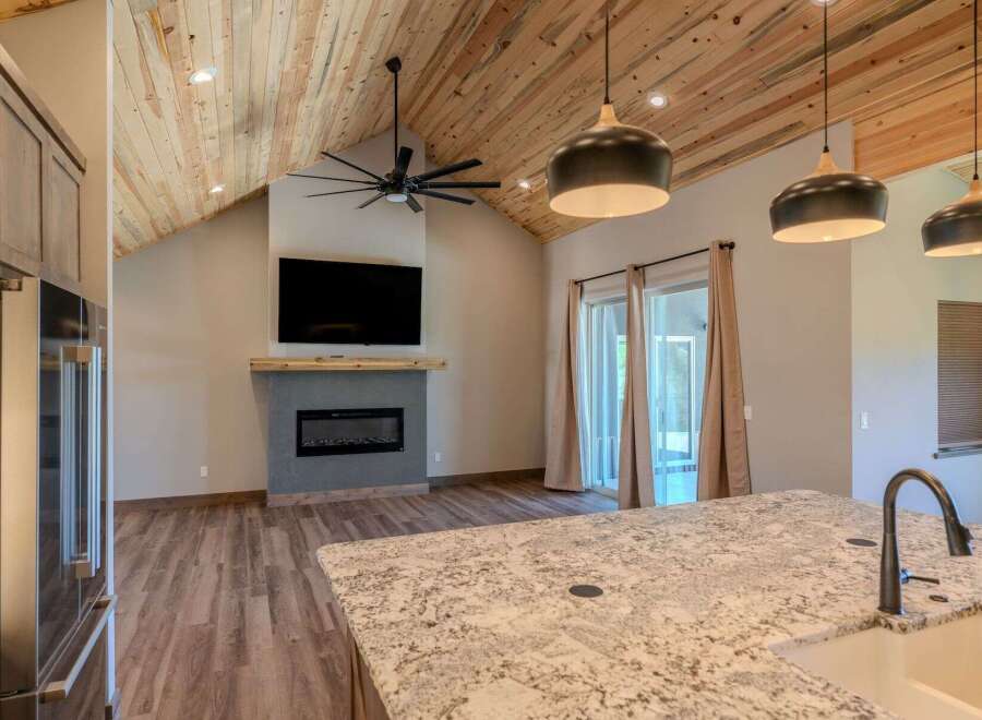 Experience modern living in this stunning home featuring a vaulted wood-paneled ceiling and a sleek fireplace as the focal point.