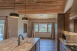 Experience breathtaking mountain views from this stunning kitchen, featuring a large granite island with a farmhouse sink and a sleek faucet.