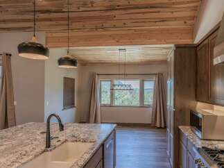 Experience breathtaking mountain views from this stunning kitchen, featuring a large granite island with a farmhouse sink and a sleek faucet.