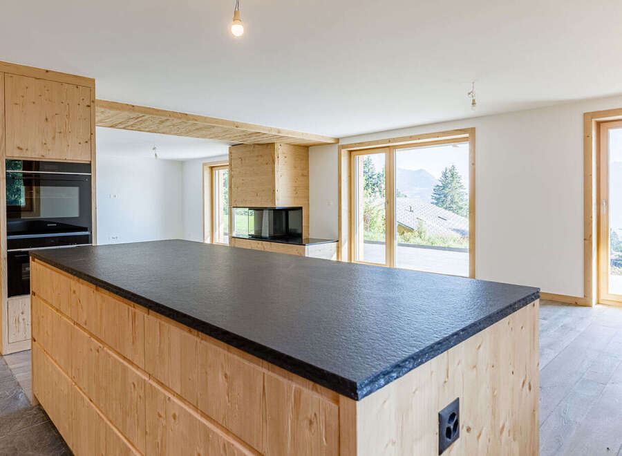 This stunning property boasts a modern kitchen with a sleek black countertop and custom wooden cabinetry.