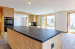 This stunning property boasts a modern kitchen with a sleek black countertop and custom wooden cabinetry.