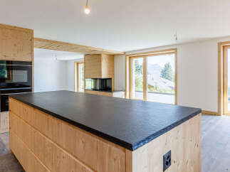 This stunning property boasts a modern kitchen with a sleek black countertop and custom wooden cabinetry.
